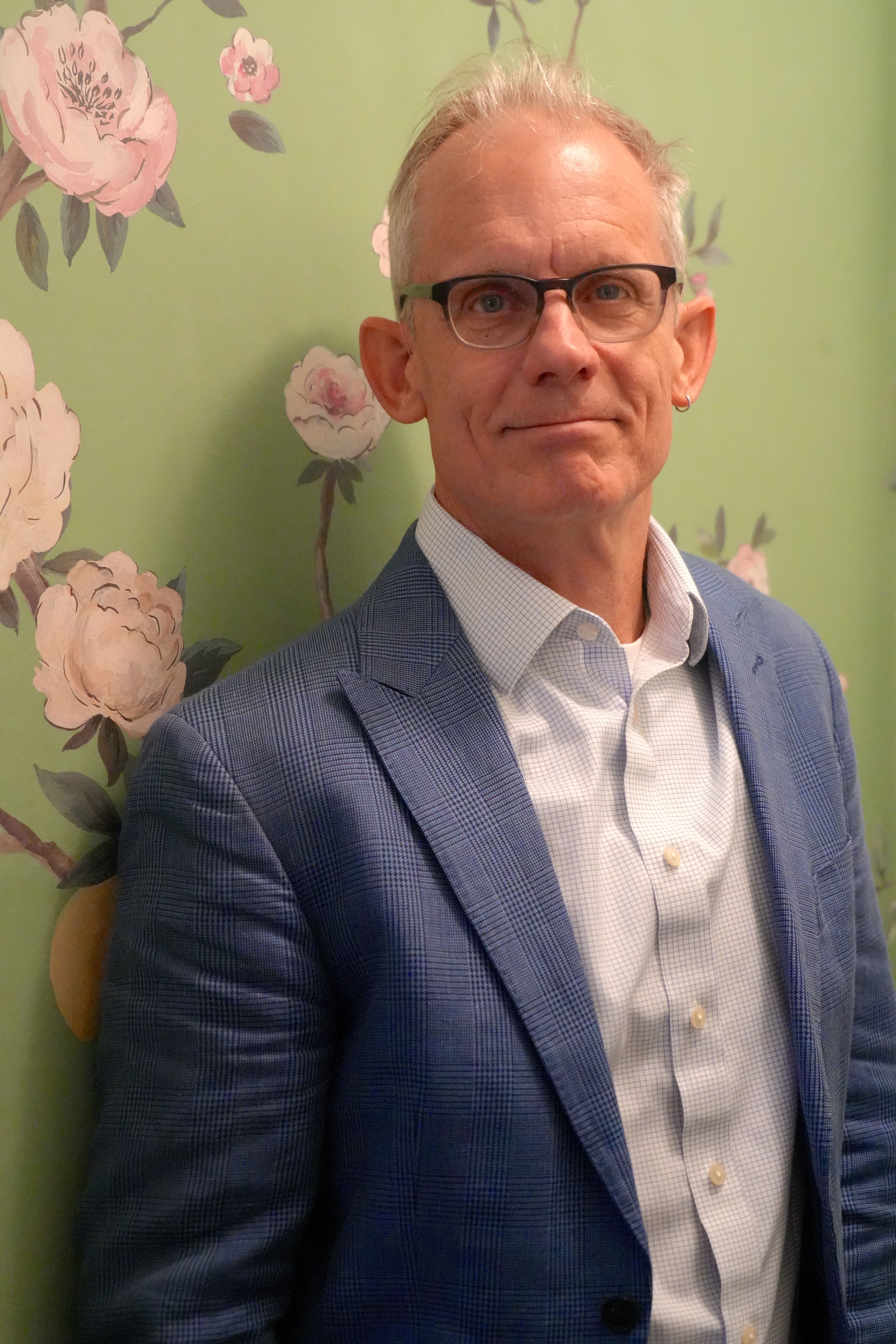 Portrait of George with green flowered wallpaper in the background.